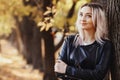 Portrait of a beautiful girl leaning on a tree trunk, a young woman walks in the autumn park on nature