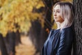 Portrait of a beautiful girl leaning on a tree trunk, a young woman walks in the autumn park on nature