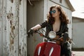 Portrait of a beautiful girl in leather jacket, brassiere and glasses near red motorcycle Royalty Free Stock Photo