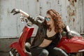 Portrait of a beautiful girl in leather jacket, brassiere and glasses near red motorcycle Royalty Free Stock Photo
