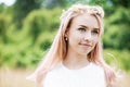 Portrait of a beautiful girl with pink hair with a wreath of daisies, close-up