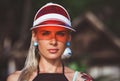 Portrait of a beautiful girl in a red visor closeup. Wearing Large turquoise earrings. Holiday in Thailand