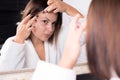 Portrait of a beautiful girl, in the reflection of the mirror. Fingers remove acne on the face