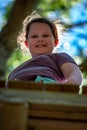 Portrait of a beautiful girl on a rope park among trees. Children summer activities.