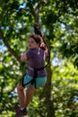 Portrait of a beautiful girl on a rope park among trees. Children summer activities.