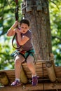 Portrait of a beautiful girl on a rope park among trees. Children summer activities.
