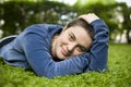 Portrait of a beautiful girl with short hair and green eyes lies on the grass, smiling and looking at the camera Royalty Free Stock Photo