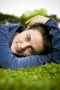 Portrait of a beautiful girl with short hair and green eyes lies on the grass, smiling and looking at the camera Royalty Free Stock Photo