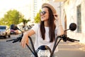 Portrait of a beautiful girl sitting on a orange motorbike, smiling and looking at the camera. Royalty Free Stock Photo