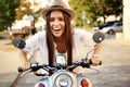 Portrait of a beautiful girl sitting on silver retro scooter, smiling and looking at the camera Royalty Free Stock Photo