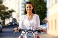 Portrait of a beautiful girl sitting on silver retro scooter, smiling and looking at the camera Royalty Free Stock Photo