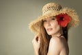 Portrait of beautiful girl in a straw hat and a red flower in her hair Royalty Free Stock Photo