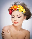 Portrait of beautiful girl in studio with red and yellow roses in her hair and naked shoulders. young woman with makeup Royalty Free Stock Photo