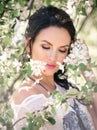 Portrait of a beautiful girl under a flowering tree. A young girl against the background of spring blooming apple trees. Close-up