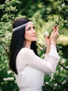 Beautiful woman in a white dress in a blooming garden. A young girl against the background of spring blooming apple trees Royalty Free Stock Photo