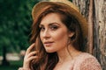 Portrait of a beautiful girl who stands near a tree. summer, walk in nature, red-haired girl in a vintage dress and a beige sweate