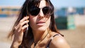 portrait, beautiful girl, woman in sun glasses talking on a mobile phone. on the beach, on a hot summer day, Royalty Free Stock Photo