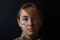 Portrait of beautiful girl with yellow and blue Ukrainian flag on her cheek wearing military uniform. Ukrainian women in the army Royalty Free Stock Photo