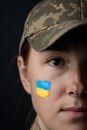 Portrait of beautiful girl with yellow and blue ukrainian flag on her cheek wearing military uniform. Ukrainian women in the army Royalty Free Stock Photo