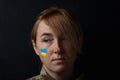 Portrait of beautiful girl with yellow and blue ukrainian flag on her cheek wearing military uniform. Ukrainian women in the army Royalty Free Stock Photo