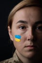 Portrait of beautiful girl with yellow and blue ukrainian flag on her cheek wearing military uniform. Ukrainian women in the army Royalty Free Stock Photo