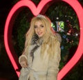 Portrait of Beautiful glamorous Blonde girl in Fur Coat posingin front of Neon Heart sign