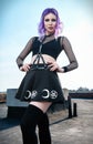 Portrait of beautiful gothic girl on housetop. Pastel goth with violet purple hair in black clothes Royalty Free Stock Photo