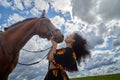 Portrait of beautiful gypsy girl with a horse on a field with green glass in summer day and blue sky and white clouds background. Royalty Free Stock Photo