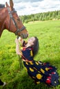 Portrait of beautiful gypsy girl with a horse on a field with green glass in summer day and blue sky and white clouds background. Royalty Free Stock Photo