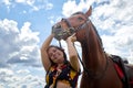 Portrait of beautiful gypsy girl with a horse on a field with green glass in summer day and blue sky and white clouds background. Royalty Free Stock Photo