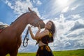 Portrait of beautiful gypsy girl with a horse on a field with green glass in summer day and blue sky and white clouds background. Royalty Free Stock Photo