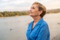 Portrait Beautiful happy active senior woman pensioner in a blue shirt smiling happily on the river bank at sunset Royalty Free Stock Photo