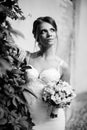 Portrait of a beautiful happy brunette bride in wedding white dress holding hands in bouquet of flowers outdoors Royalty Free Stock Photo