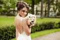 Portrait of a beautiful happy brunette bride in wedding white dress holding hands in bouquet of flowers outdoors Royalty Free Stock Photo