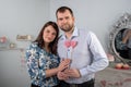 Portrait of a beautiful happy couple hugging, standing close, smiling, holding two hearts in their hands at home