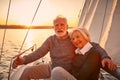 Portrait of a beautiful and happy senior couple in love hugging and enjoying amazing sunset while sitting on the side of Royalty Free Stock Photo