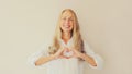 Portrait of beautiful happy smiling caucasian middle aged woman showing heart shaped gesture sign with hands on her chest looking Royalty Free Stock Photo