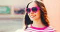 Portrait of beautiful happy smiling young brunette woman in red heart shaped sunglasses on pink background Royalty Free Stock Photo