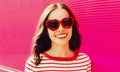 Portrait of beautiful happy smiling young brunette woman in red heart shaped sunglasses on pink background Royalty Free Stock Photo