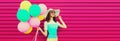 Portrait of beautiful happy smiling young woman with bunch of balloons wearing a colorful dress on pink background Royalty Free Stock Photo