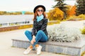 Portrait of beautiful happy smiling young woman model wearing black round hat, leather jacket, sunglasses in the city street Royalty Free Stock Photo