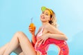 Portrait of beautiful happy woman in bathing suit sitting sexy and smiling to camera, holding rubber ring, fresh juice or cocktail Royalty Free Stock Photo