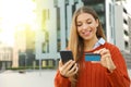 Portrait of a beautiful happy woman enter the credit card number for buying online with a smart phone outdoors Royalty Free Stock Photo