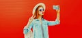 Portrait of beautiful happy woman taking selfie by smartphone blowing her lips wearing summer straw round hat, backpack on red Royalty Free Stock Photo