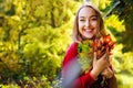 Portrait of a beautiful happy young woman with a bouquet of yellow leaves in an autumn park. A pretty Caucasian lady smiles and