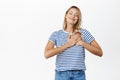 Portrait of beautiful happy young woman dreaming, holding hands on heart, smiling with eyes closed, thinking of smth Royalty Free Stock Photo