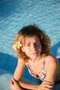 portrait of beautiful happy young woman, slender teenage girl, with curly hair, is relaxing in the water of the pool