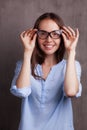 Portrait of beautiful happy young woman wearing glasses near grey grunge wall Royalty Free Stock Photo