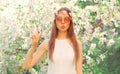 Portrait of beautiful hippie woman wearing floral headband, sunglasses in spring blooming garden on flowers background Royalty Free Stock Photo