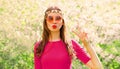 Portrait of beautiful hippie young woman blowing her lips sending air kiss wearing floral headband, sunglasses in spring blooming Royalty Free Stock Photo